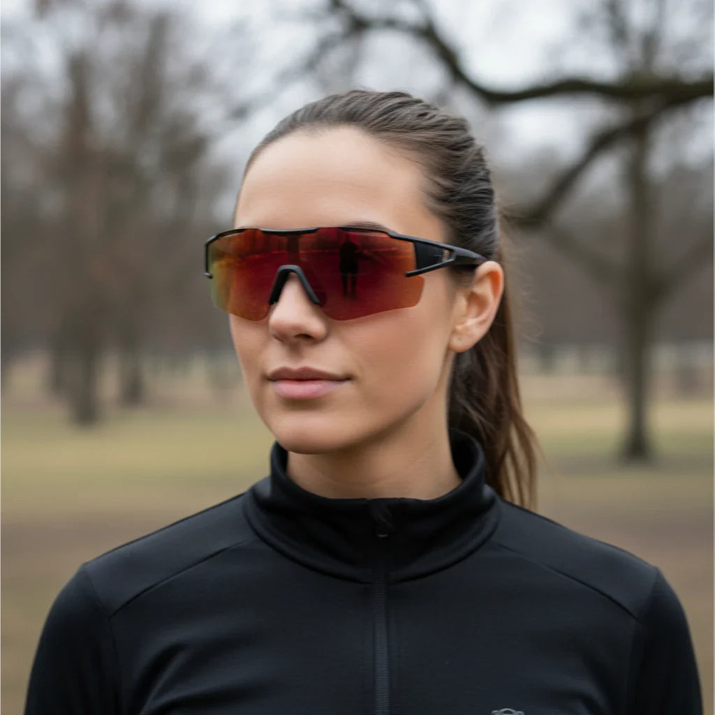 Kvinde iført Sprinta løbebriller med orange spejllinse under udendørs træning – sporty design med UV400-beskyttelse og let pasform til løb og cykling