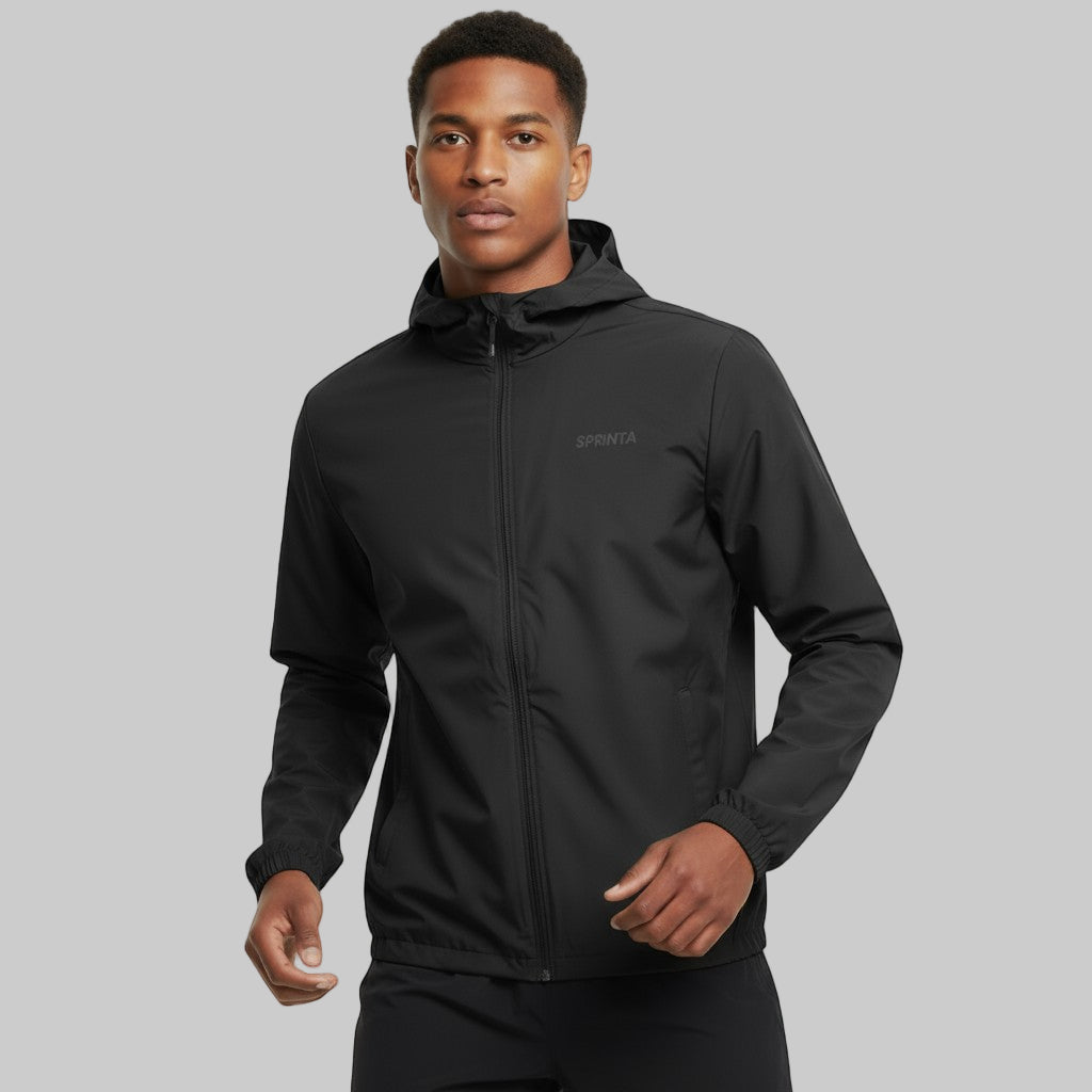 Mand iført sort Sprinta letvægts løbejakke står i studiemiljø og kigger fremad.