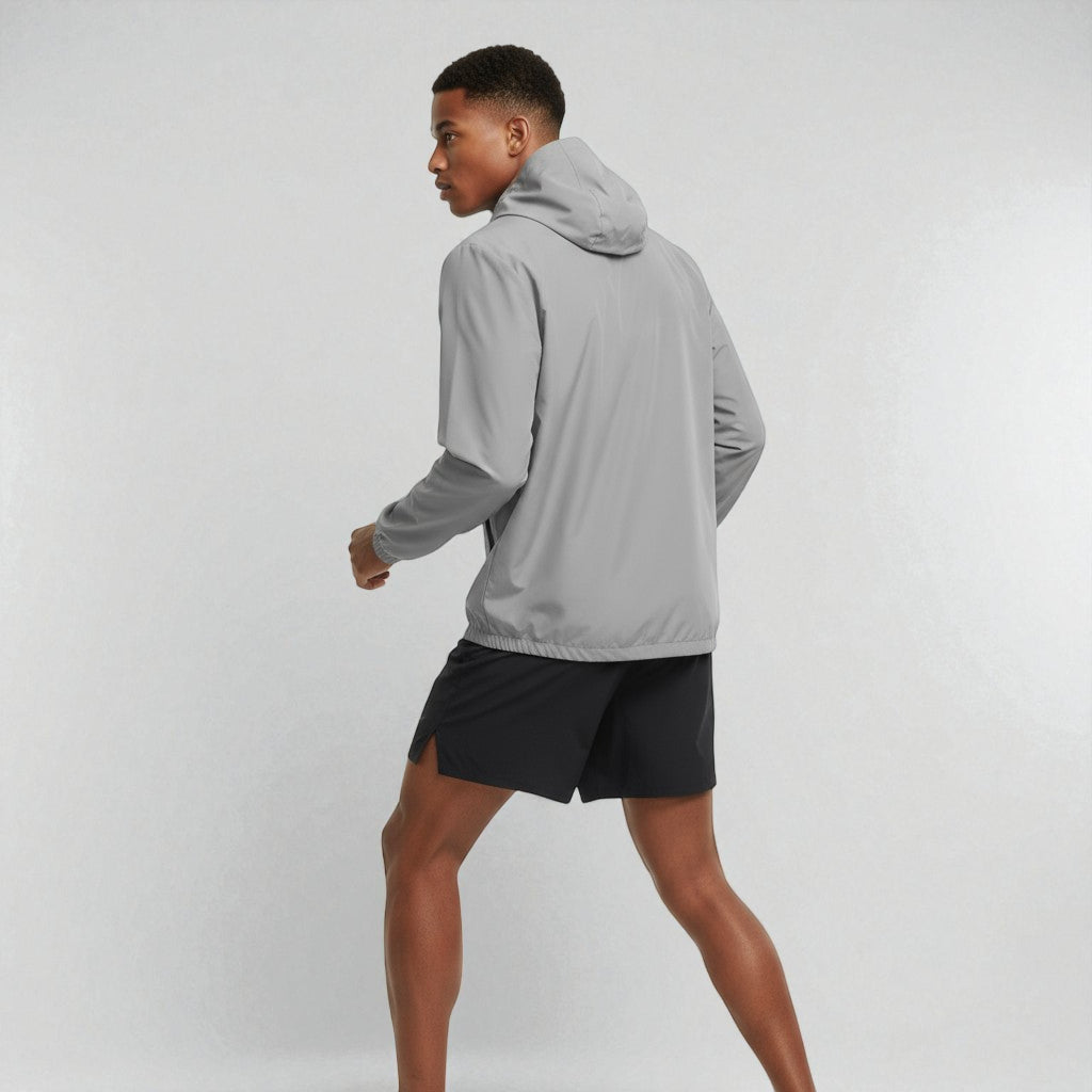 Mand set bagfra ifoert graa Sprinta letvaegtsjakke og loebeshorts, klar til udendoerstræning.