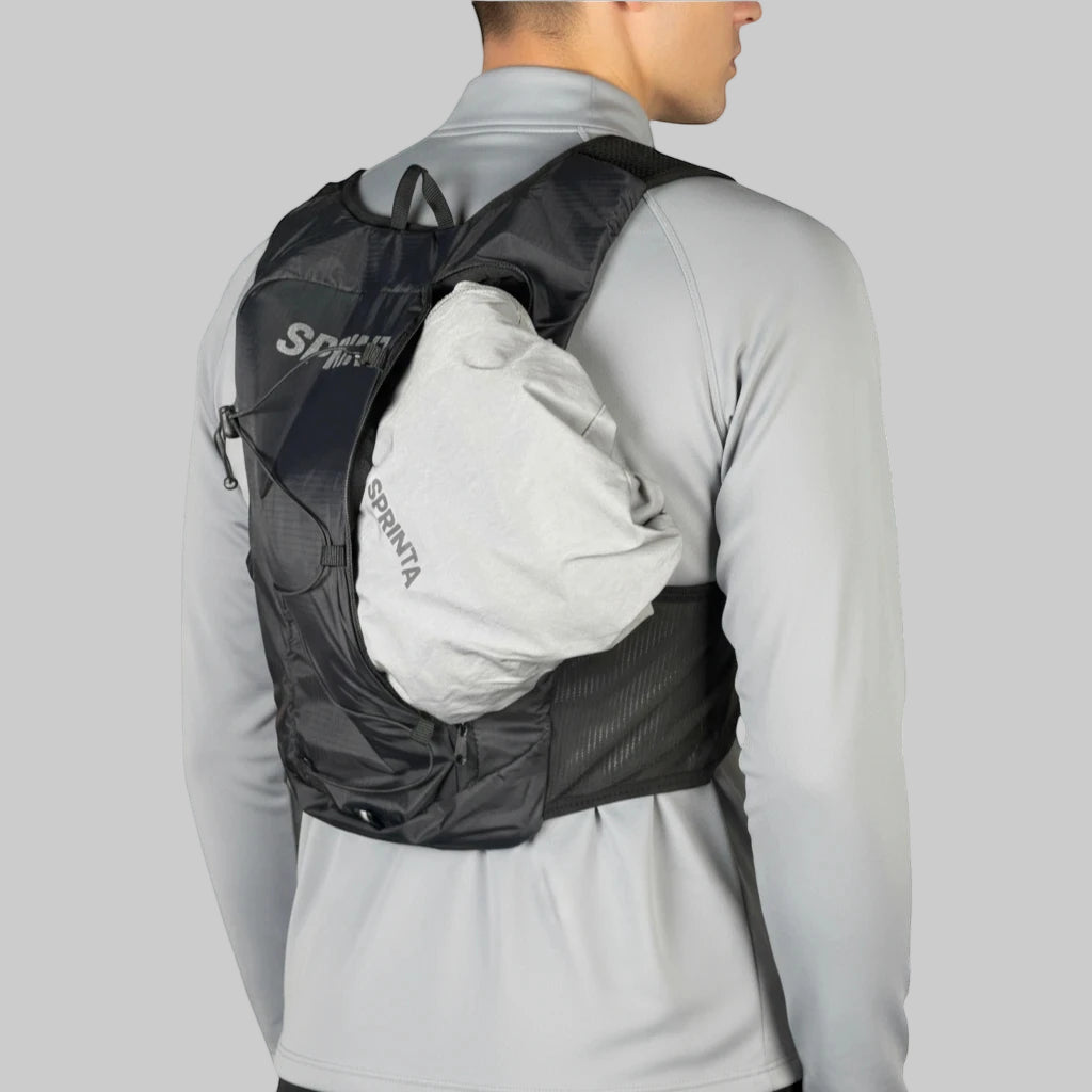 Mand med sort løbevest der viser udvidet baglomme med pakket løbejakke.