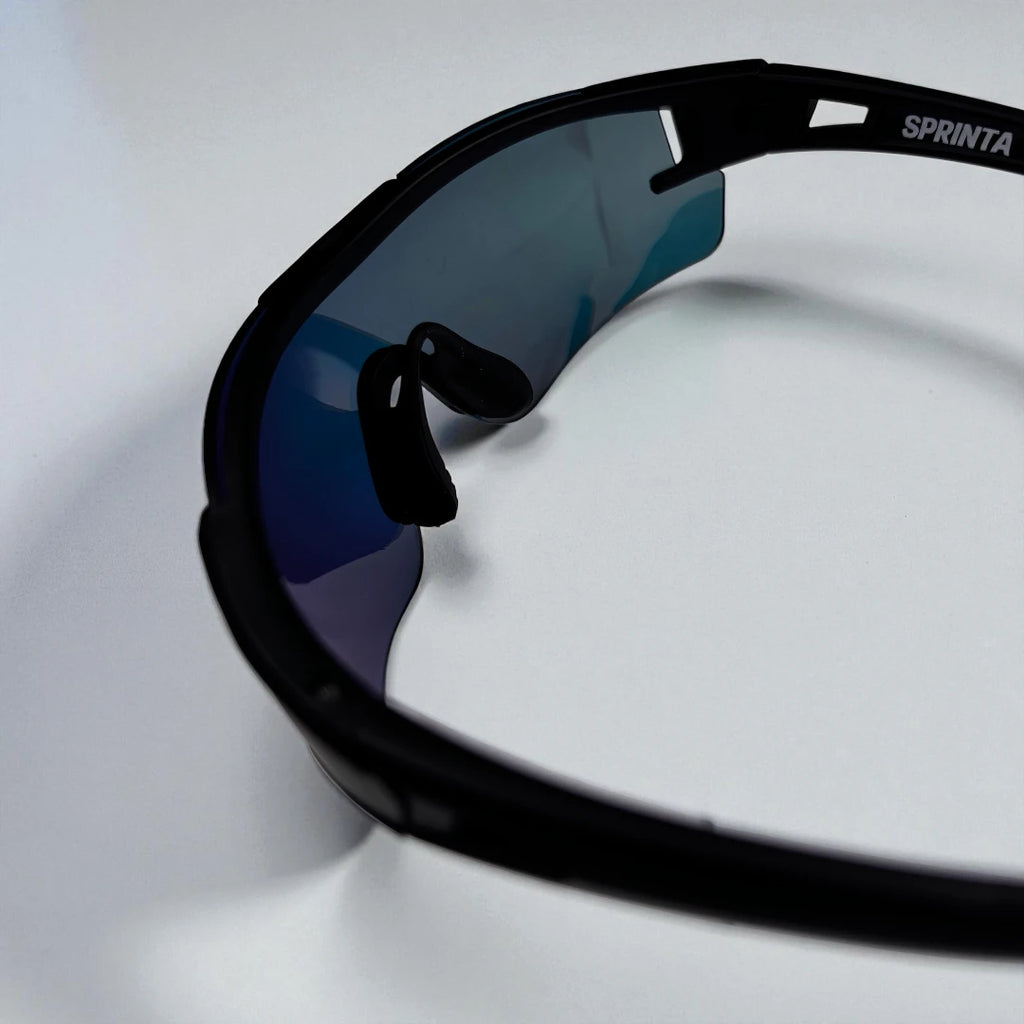 Detaljebillede af Sprinta Performance løbebriller – sorte sports solbriller med fleksibelt næsestykke og orange spejllinse, designet til løb og træning med høj komfort og ventilation