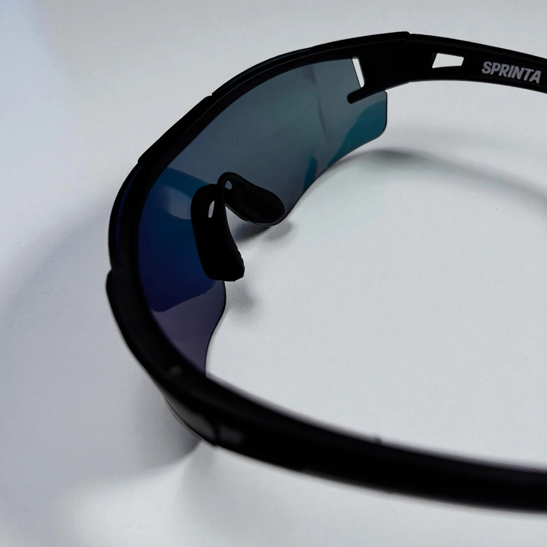 Detaljebillede af Sprinta Performance løbebriller – sorte sports solbriller med fleksibelt næsestykke og orange spejllinse, designet til løb og træning med høj komfort og ventilation